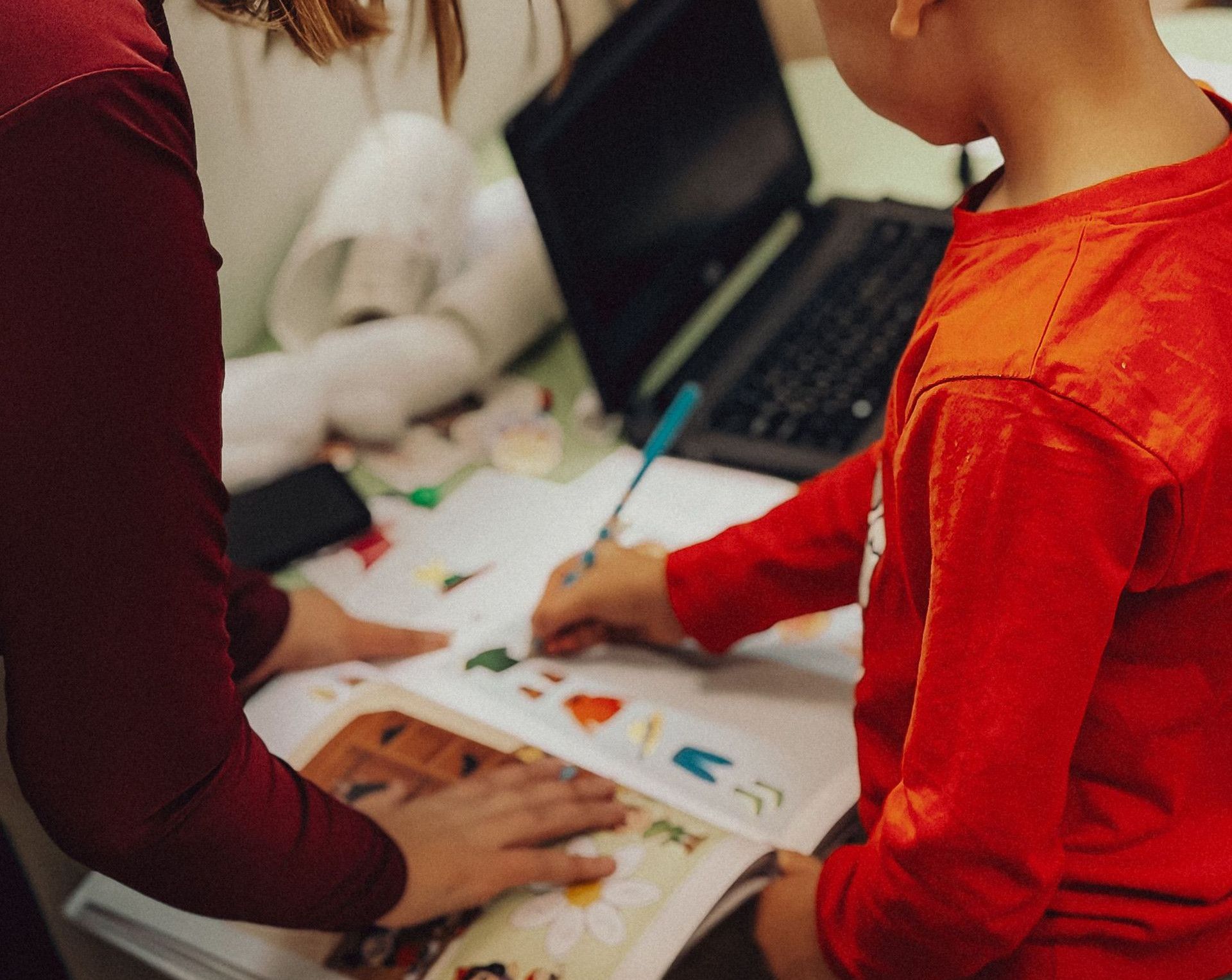 Teacher assisting a child with educational activities in a learning environment.