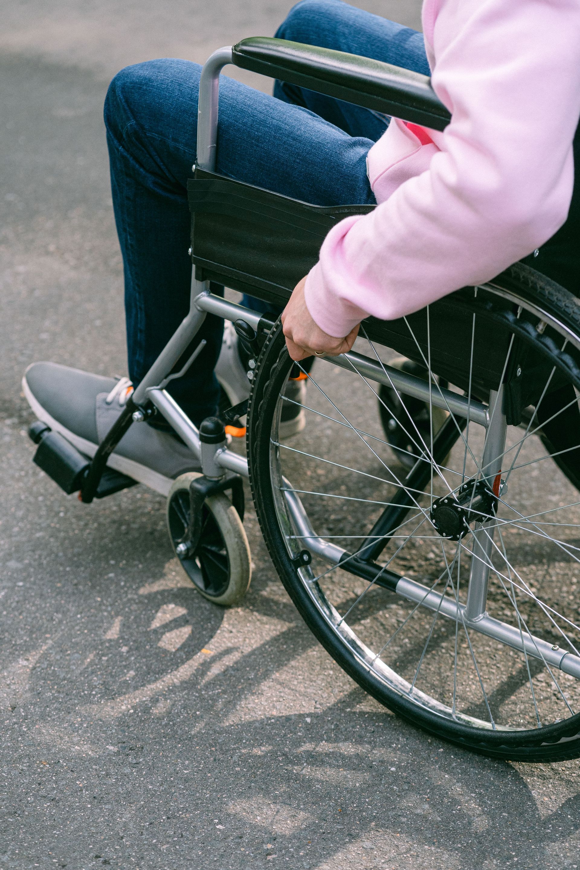 Close-up of an adult managing a wheelchair outdoors on a sunny day, emphasizing independence.