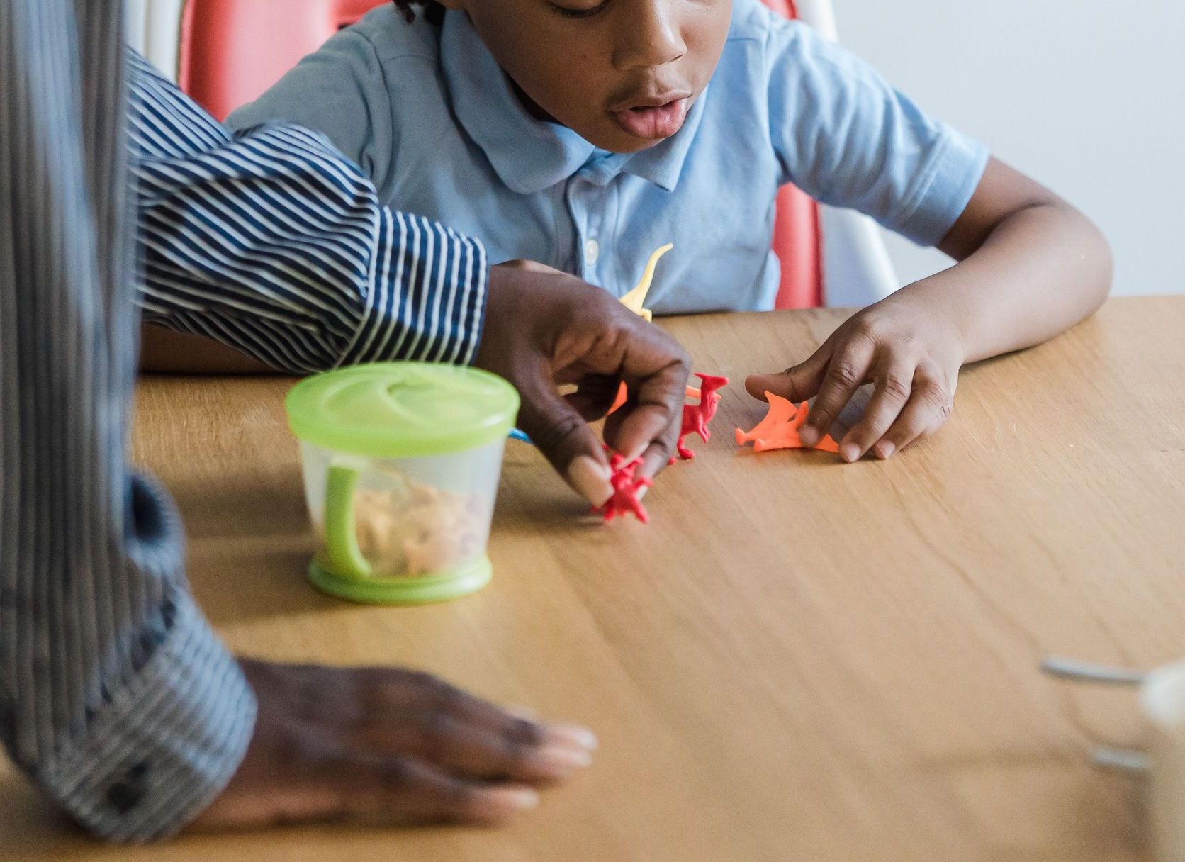 A mother and daughter enjoying playtime with toys at a table indoors.